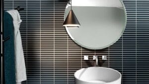 Modern bathroom with round mirror, black wall tiles, and contemporary sink for stylish home renovation.