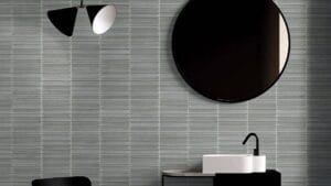 Sleek modern bathroom with minimalist black and white fixtures, textured gray tiled wall, round mirror, and contemporary sink and faucet, showcasing stylish home renovation ideas.