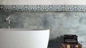 Sleek modern bathtub with a minimalist chrome faucet set against a textured concrete wall and decorative tile border. Stylish bath design ideal for contemporary bathroom renovations.