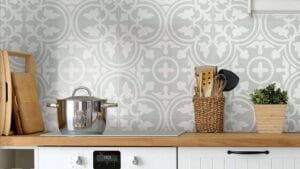 Sleek kitchen backsplash with elegant gray and white geometric tile design, featuring cooking utensils, wooden cutting boards, and potted plant, creating a stylish and functional kitchen space.