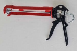 Sealing gun with red and black handle, metal trigger, and long nozzle, used for construction and DIY sealing applications. High-quality caulking gun for professional and home improvement projects.
