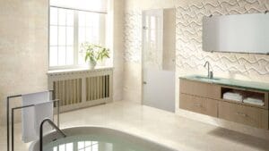 Modern beige bathroom with vanity, glass countertop, wall-mounted mirror, and decorative textured wall art, featuring a bathtub, towel rack, and large window for natural light.