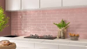 Vibrant pink subway tile backsplash in a modern kitchen with marble countertop, decorative plants, and cooking essentials, showcasing trendy kitchen decor and renovation ideas.
