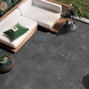 Tile Samples 30 Textile outdoor furniture with beige cushions and a black round side table on a modern outdoor patio with dark grey flooring and greenery.