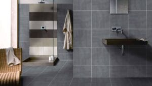 Complete Bathroom Packages: Simplify Your Reno with Style 4 Modern grey and beige tiled bathroom with walk-in shower, wall-mounted sink, and minimalist fixtures, showcasing contemporary bathroom design and durable wall and floor tiles.