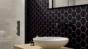 Elegant bathroom with black honeycomb tile accent wall, modern matte black fixtures, and a sleek vessel sink, showcasing stylish and durable bathroom renovation ideas from Builders Warehouse Online.