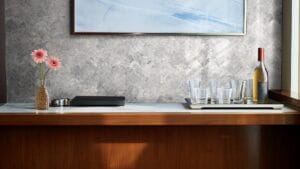 Elegant bar area with a wooden countertop, pink daisy flowers in a woven vase, glassware, and a wine bottle, perfect for home entertaining and stylish decorating.