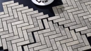Elegant grey stone patio pavers arranged in a geometric herringbone pattern for outdoor landscaping and walkway design. Durable natural stone tiles ideal for garden paths and driveways.