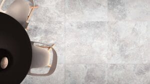 Smooth grey stone tile flooring in a modern interior with a stylish round black table and white chairs. Perfect for homeowners seeking durable, contemporary flooring solutions from Builders Warehouse Online.