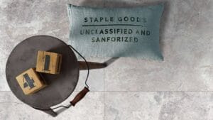 Steel bucket with wooden blocks and black letters on marble floor, ideal for construction and DIY projects.