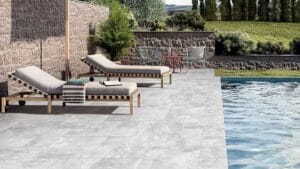 Modern outdoor poolside lounging area with sunbeds, stylish chairs, and lush greenery, ideal for backyard entertainment and relaxation.