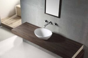 Sleek modern bathroom vanity with a round vessel sink and wall-mounted faucet featuring gray tiles and a wooden countertop, perfect for contemporary home renovation projects.