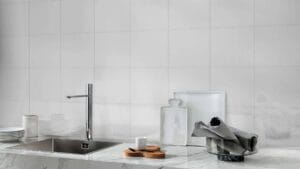 Sleek modern kitchen sink with chrome faucet, white backsplash tiles, and minimalist countertop accents. Ideal for contemporary kitchen renovations with high-quality fixtures and stylish decor.