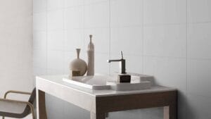 Modern bathroom vanity with stylish ceramic sink and sleek chrome faucet, decorated with minimalist vases and a soap dispenser, set against a clean white tiled wall, showcasing contemporary bathroom design.