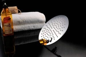 Shower care body shower gel, white towels, and a modern showerhead on black reflective surface, showcasing shower and bath accessories from Builders Warehouse Online for home renovation and bathroom upgrades.