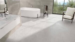 Bright modern bathroom with minimalist white vanity, free-standing bathtub, large window with scenic views, and stylish chairs, featuring neutral tones and sleek fixtures.