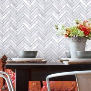 Colorful flower arrangement in a rustic stone vase on a modern dining table with white and wooden plates, against a stylish white herringbone tile backsplash, perfect for contemporary home decor.