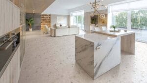 Polished marble kitchen island and modern interior design featuring natural stone surfaces, neutral tones, and contemporary furnishings in a bright open-plan living space.