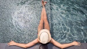 Relaxing poolside with a woman sunbathing, showcasing outdoor pool tiles and backyard leisure area at Builders Warehouse Online.