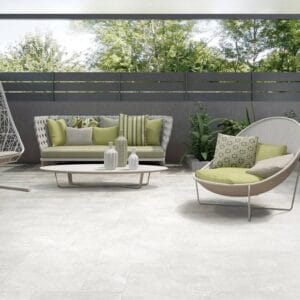 Modern outdoor patio furniture set with green cushions and decorative pillows, perfect for outdoor living and garden relaxation. Stylish seating arrangement on a spacious patio with lush green background.