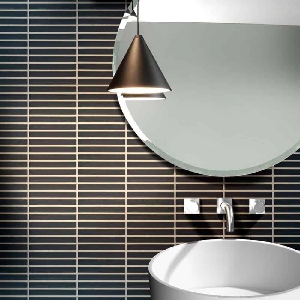 Modern bathroom with black tiled wall, round mirror, sleek black pendant light, and white sink for stylish home renovation.