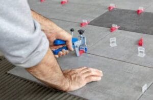 How To Choose The Right Tiler For Your Project 6 Precision tile installation with tile spacers and leveling system on concrete floor, highlighting professional tiling techniques for home renovation projects.