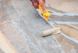 Painted concrete floor with roller and paintbrush for surface sealing or coating.