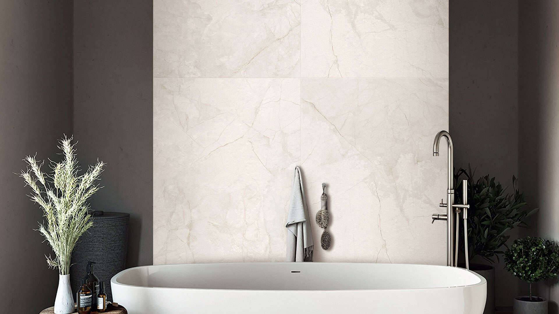 Luxurious white freestanding bathtub with modern chrome faucet in minimalist bathroom with marble wall accents, greenery, and natural decor for a stylish home spa.