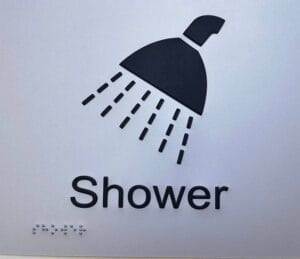 AS 1428.1 Accessibility Compliance: Essential Guide 10 Shower icon sign with Braille text, modern design for bathroom signage and accessibility, representing shower facilities in residential or commercial buildings.
